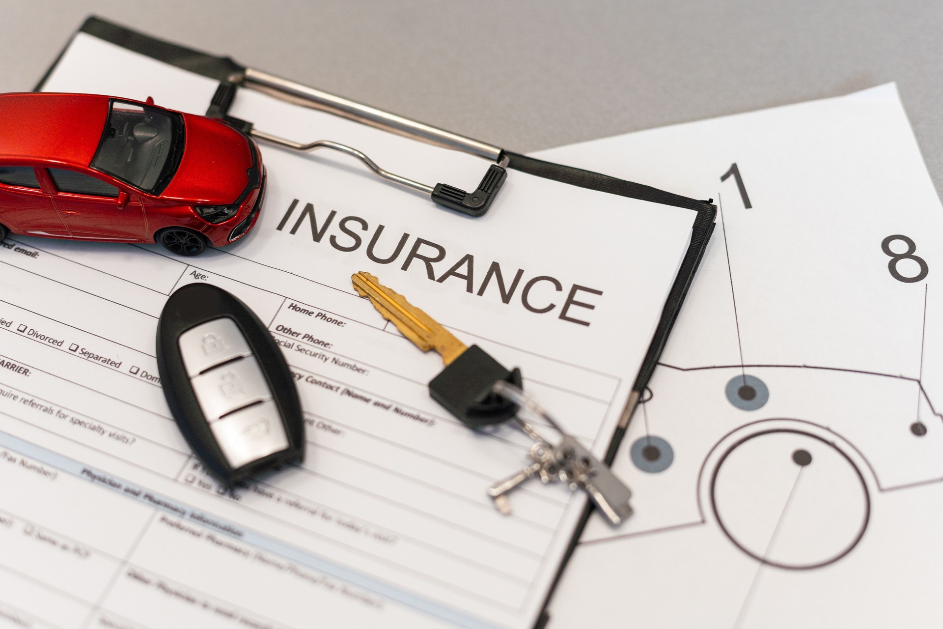 Top view of car insurance claim form with car key and car toy on desk
